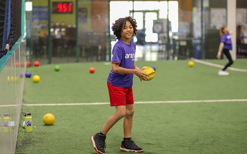 A child throws a ball during field games at camp at Arena Sports