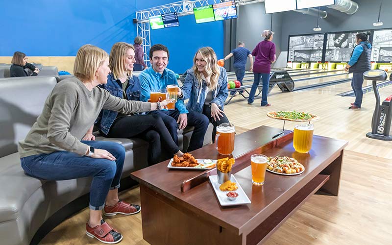 A group of adults enjoy snacks and drinks while bowling at Arena Sports Mill Creek