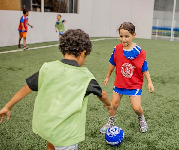 Two children practice soccer in a Lil' Kickers class at Arena Sports