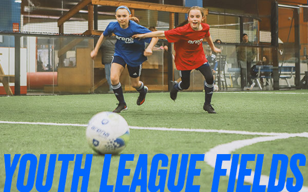 Two girls run towards a soccer ball at an indoor soccer field at Arena Sports