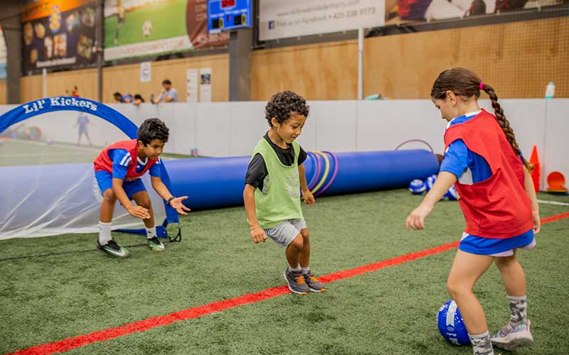 Young kids learn a soccer drill from a Lil' Kickers coach