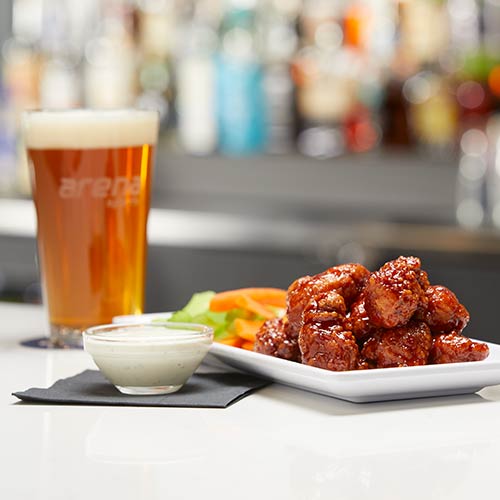 A plate of bbq boneless wings and a glass of beer from Moe's Kitchen & Bar in Arena Sports Issaquah