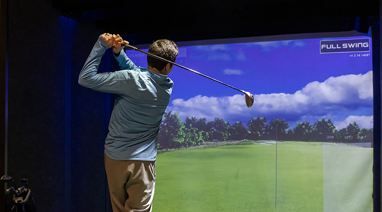 A man practices his golf swing in the Golf Lounge at Arena Sports in Issaquah