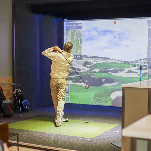 A person just finished their golf swing in the Golf Simulator at Arena Sports Issaquah