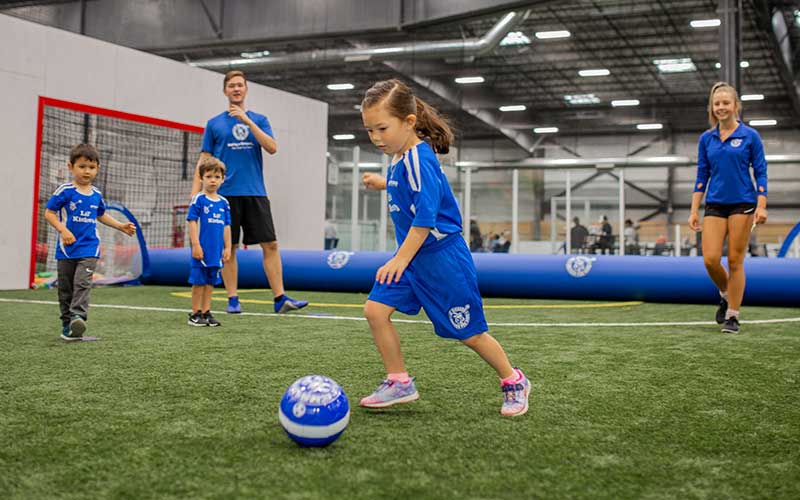 Kids and coaches have fun playing soccer in a Lil' Kickers class at Arena Sports