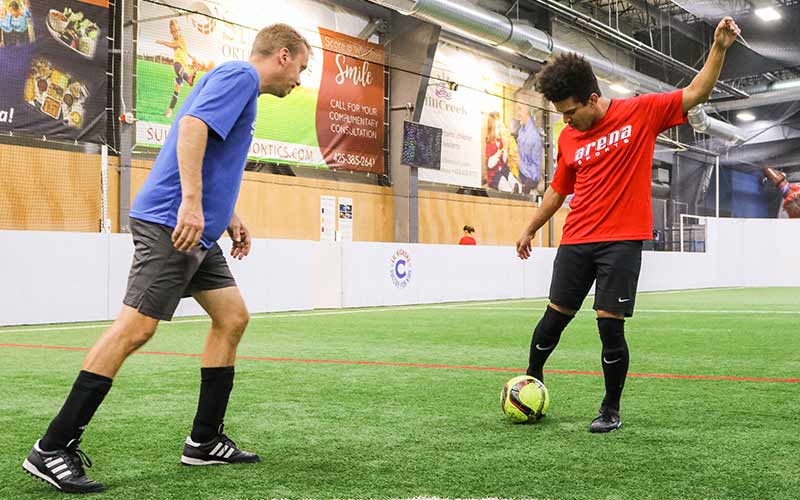 Two adult league players square off at the soccer ball at Arena Sports