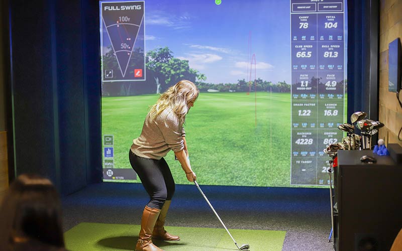 A woman tees up at the Golf Simulator at Arena Sports Issaquah