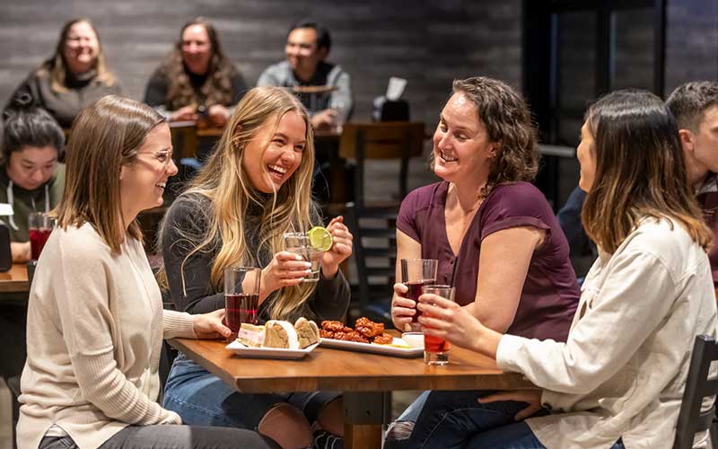 A group of women laugh together while enjoying drinks & appetizers at Moe's Restaurant & Bar