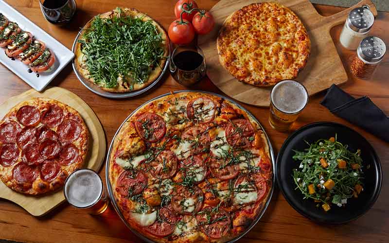 view from above of a variety of pizzas and salads available from Moe's Restaurant & Bar