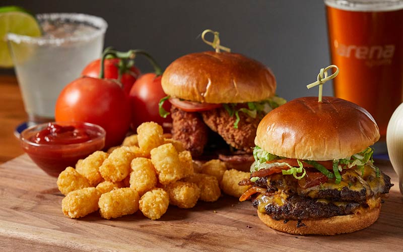 Photo of gourmet burgers, tater tots, and beverages