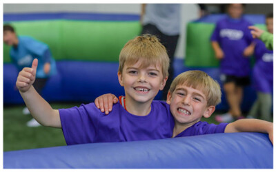 Two boys smile and give a thumbs up during Summer Camp at Arena Sports