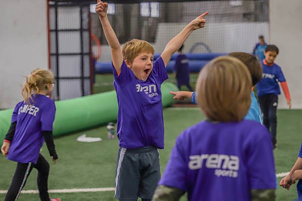 A boy celebrates a fun summer camp day during field games at Arena Sports